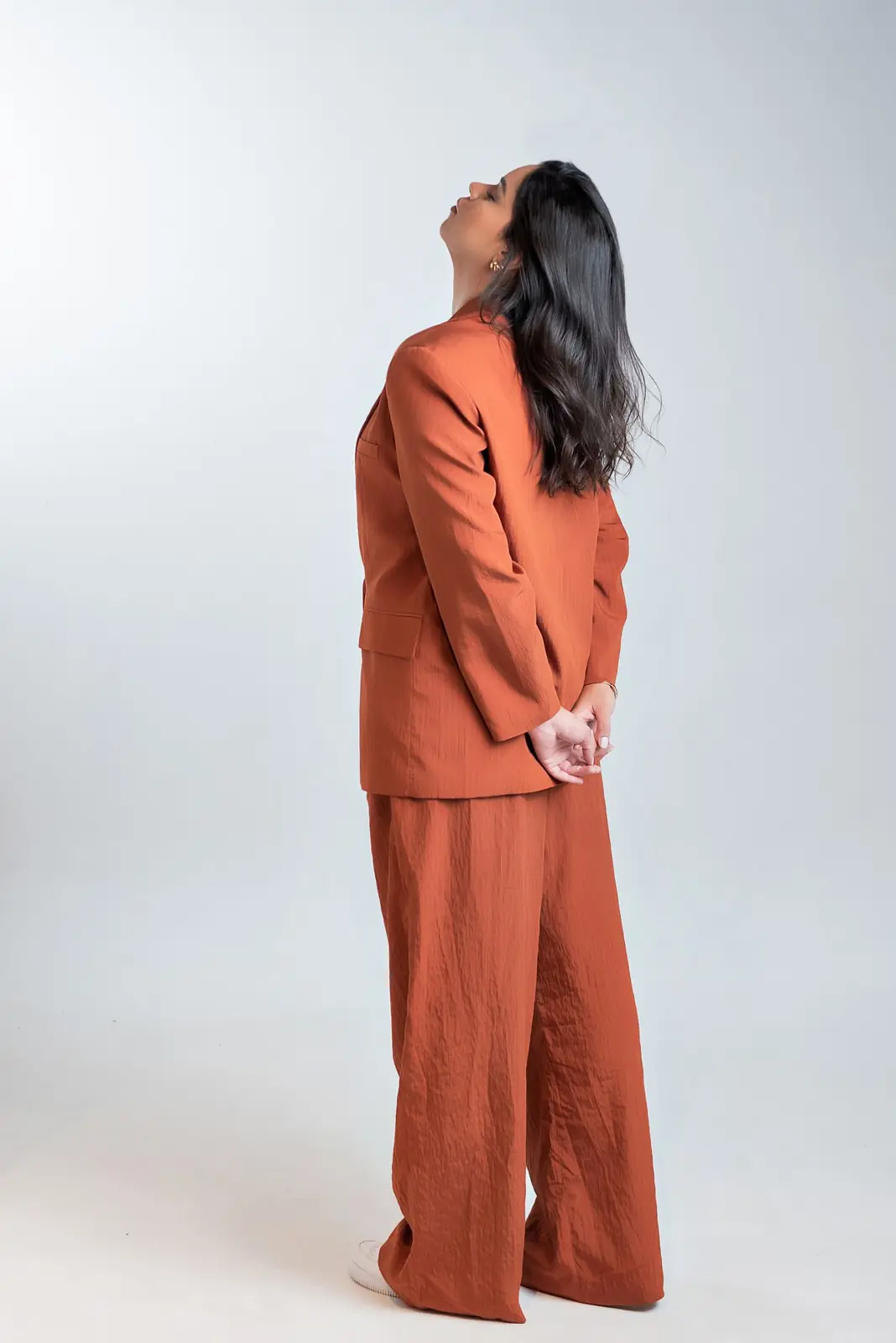 Bruna de terno laranja em estúdio, olhando para cima