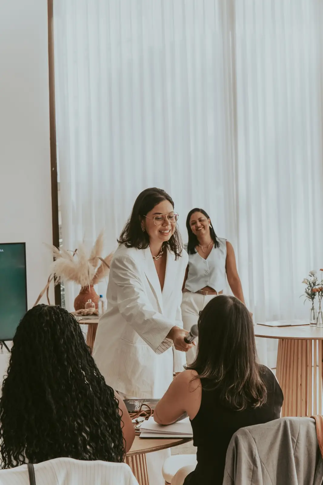 Bruna cumprimentando participantes de um encontro