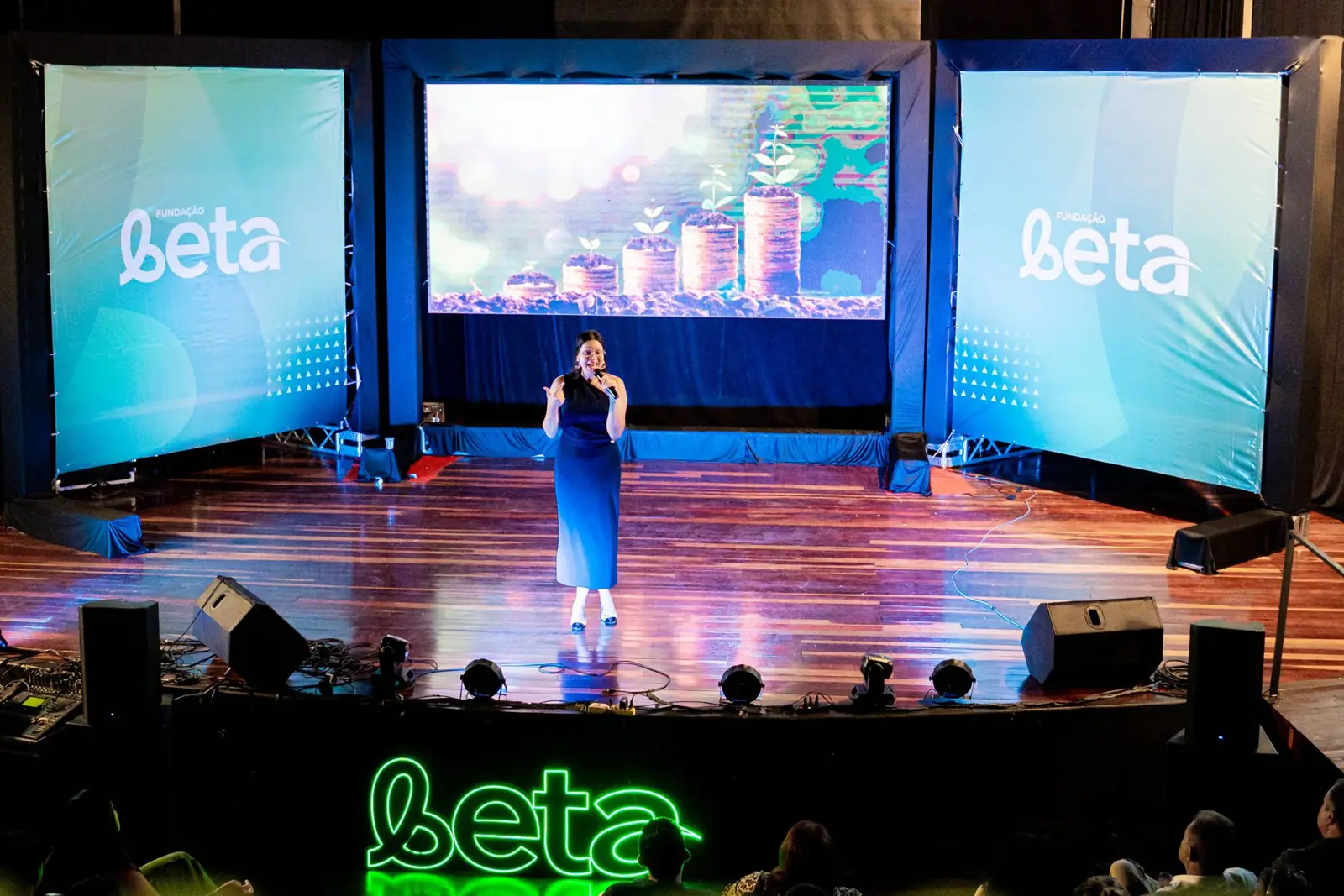 Bruna palestrando em um grande palco, diante da plateia